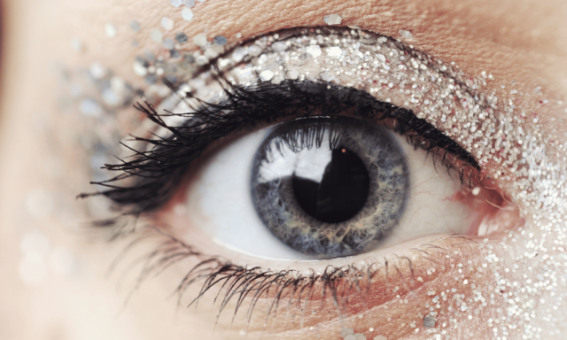 Macro view of a girl's eye with glitter makeup and eyeshadow.