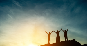 NOV 5 | 2024 Women’s Leadership Conference 3 women in silhouette on a mountaintop with joined, raised hands
