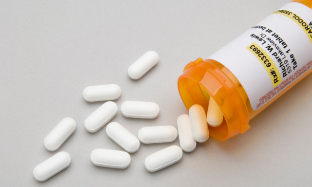 Pills spilling out of a prescription bottle on a table