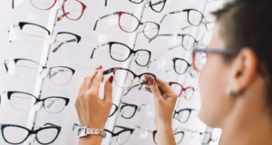 OCT 27 | Virtual CE: Grow Specialty Eye Care By Harvesting Patient Trust Woman lifting a pair of glasses from a display in an optical store