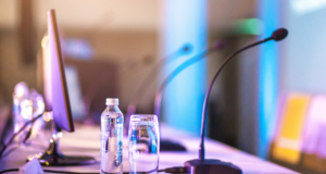 The Optometry Conferences We’re Eyeing in 2025 view of a conference panel table with microphones and water bottles