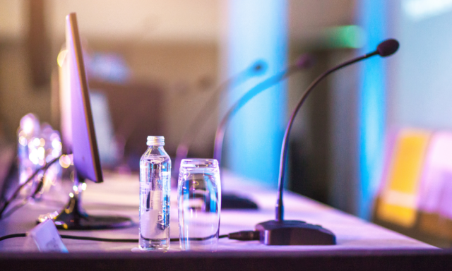 view of a conference panel table with microphones and water bottles