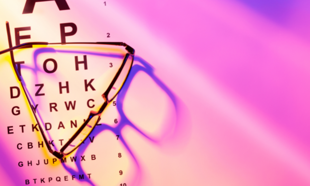 glasses on top of an eye chart with pink light shining