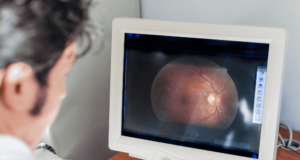 MAR 30 | Virtual CE: Refer This, Not That: Retinal Decision Making Optometrist looking at an image of a retina on a monitor
