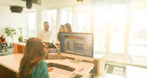 Meeting the Moment: How Optometry Practices Are Adapting to Staffing Pressures medical receptionist at a desk with patients in background