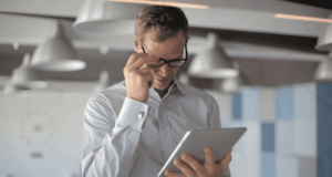 What Are Adaptive AI Intake Forms and Are They Worth Implementing in Your Practice? Man with glasses looking at a tablet