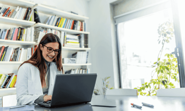 Doctor smiling while on a laptop in her office