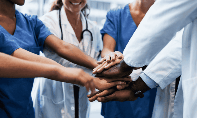 A group of healthcare professionals stacking hands
