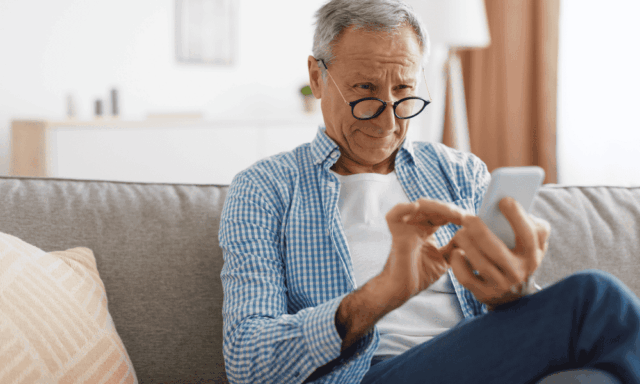 Man with glasses squinting at his phone