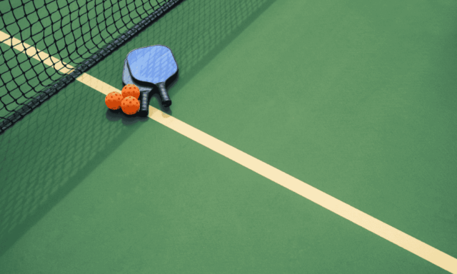 overhead view of pickleball court with balls and rackets placed near the net